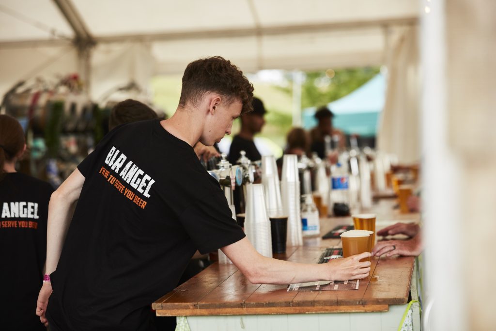 A bar tender serves a beer in the ABR village