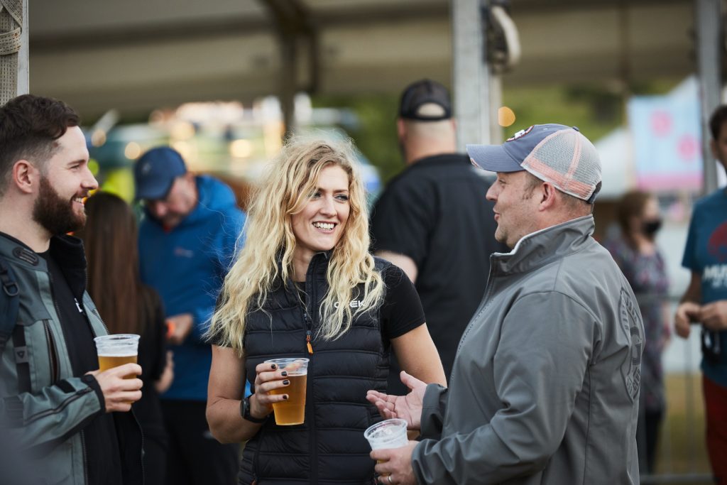 A woman and two men socialise at the Adventure Bike Rider Festival