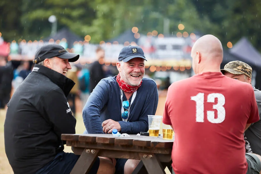 A group of men laughing at a table in the ABR Village