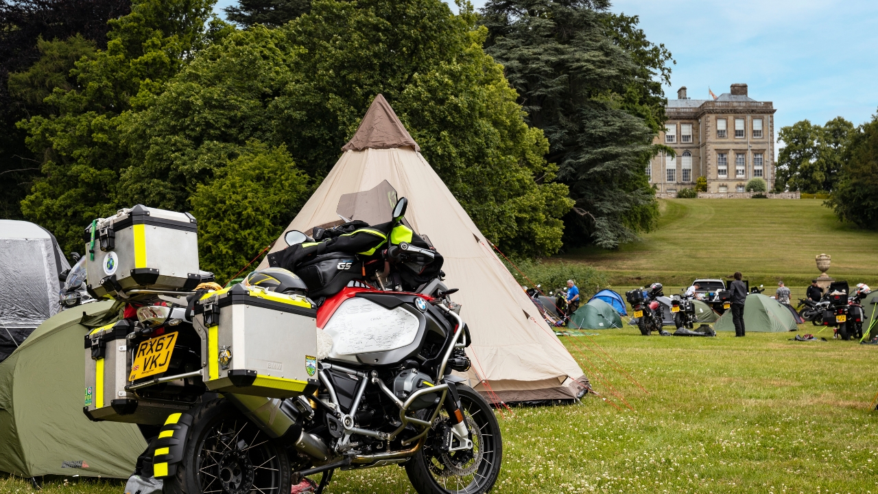 A motorcycle and tent with the Great Hall in the background